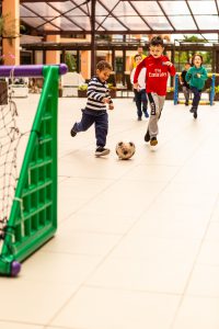 crianças jogando bola em espaço interno