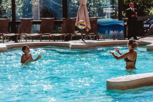 piscina com duas pessoas brincando de passar uma bola de vôlei