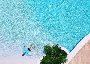 piscina que imita uma praia com uma pessoa boiando na água