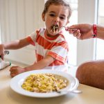 criança comendo macarrão