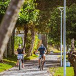 homem e mulher caucasianos andando de bicicleta em ciclovia