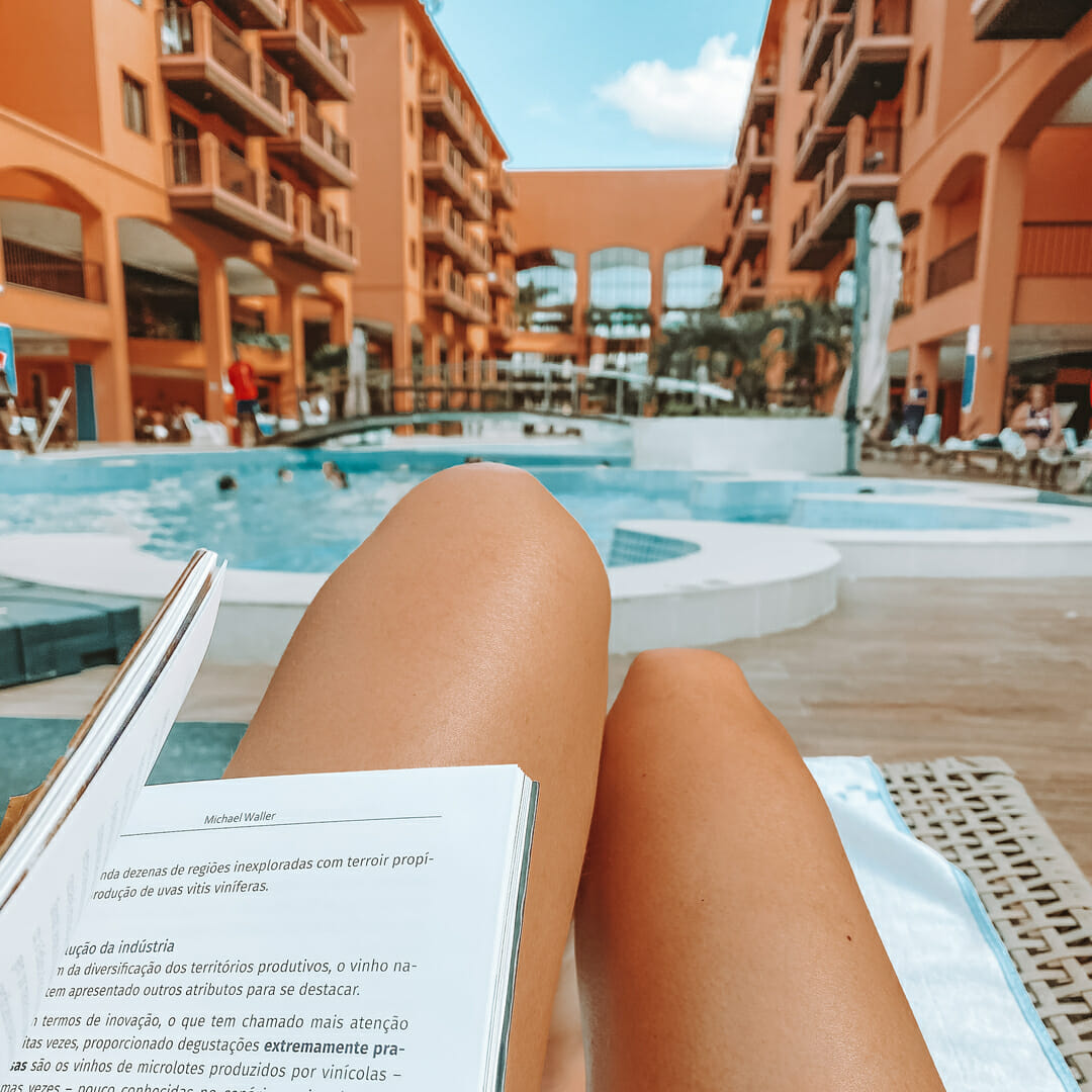 mulher lendo livro na beira da piscina