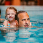 pai nadando com sua filha na piscina