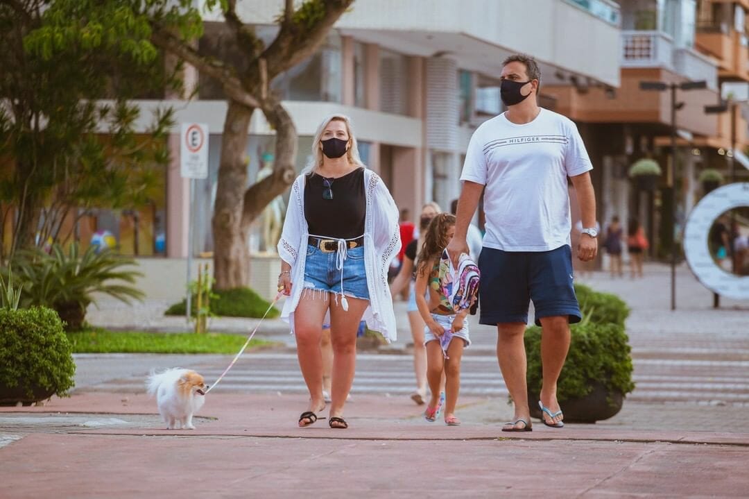 família composta por mãe, pai e filha caucasianos passeando com o cachorro em Jurerê Open Shopping